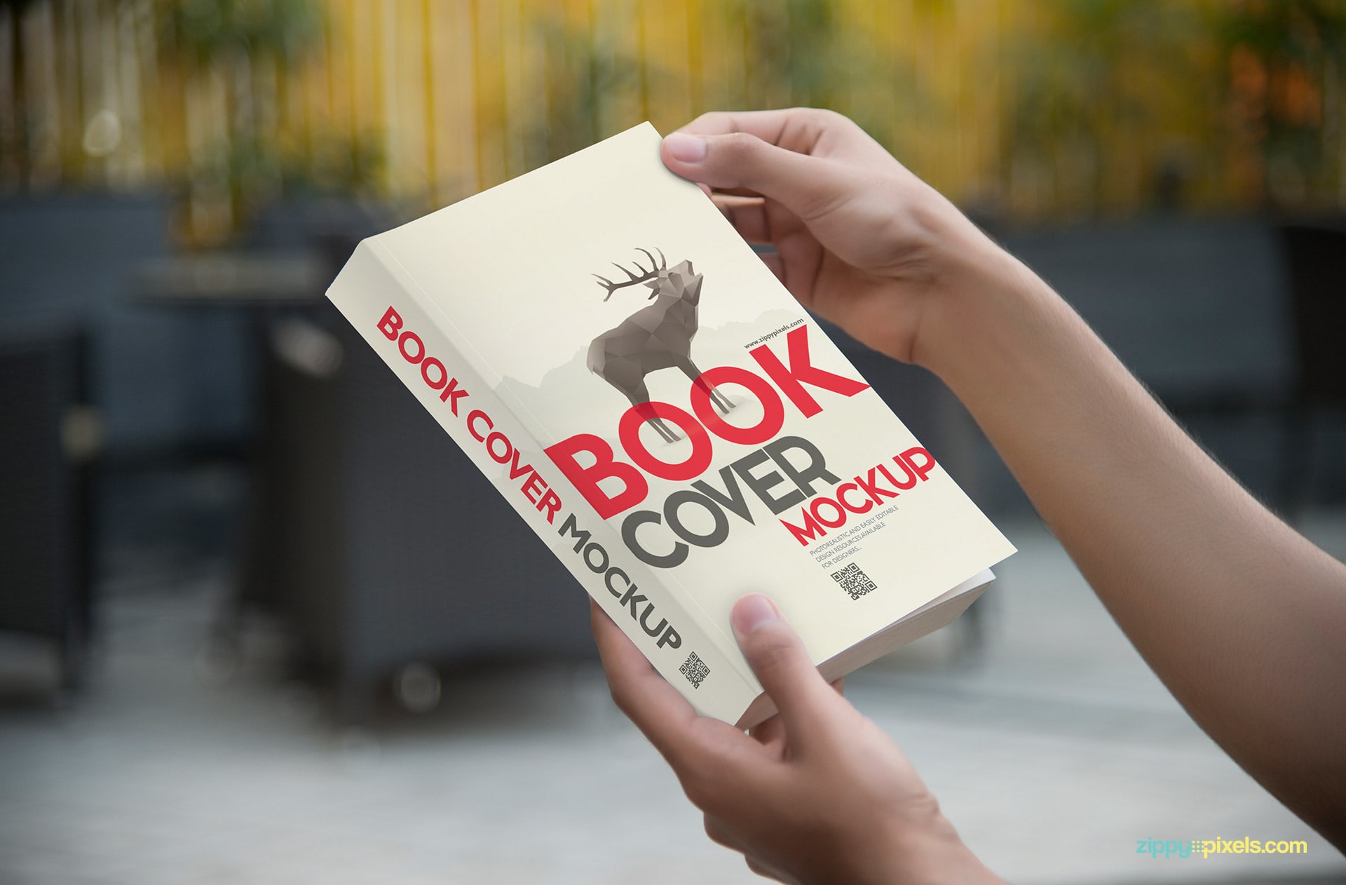 Mockup of softcover book held in hands showing front cover in a closeup